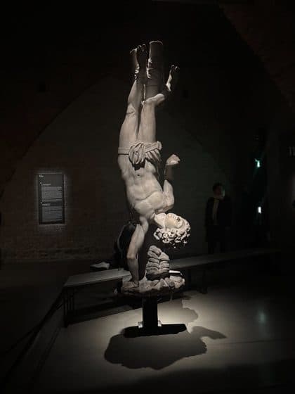 An upside-down marble statue in a dark hall